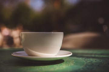 Coffee mug on mint green table outdoor background - soft light effect style pictures