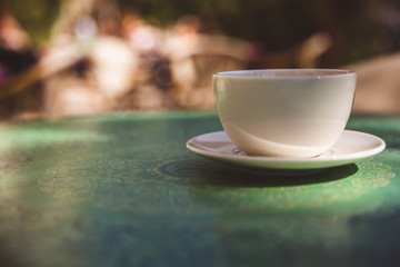 Coffee mug on mint green table outdoor background - soft light effect style pictures