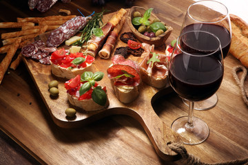 antipasto various appetizer. Cutting board with prosciutto, salami, cheese, bread and olives on dark wooden background