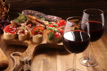 antipasto various appetizer. Cutting board with prosciutto, salami, cheese, bread and olives on dark wooden background
