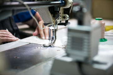 Woman hands sews clothes made of cloth on a sewing machine. Women hands using sewing machine. Clothing industry