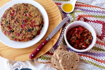 Tortilla de pisto sobre plato blanco y fondo madera y crochet