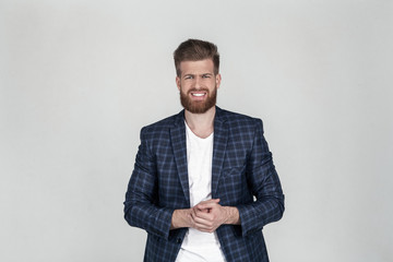 A beautiful sexy bearded business man in a jacket looks at the camera. he had a problem. He shrugged from pain, standing in front of a white background