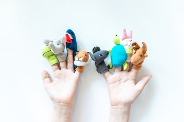 Hands of a child with finger puppets, toys, dolls close up on white background - playing puppet theatre and children entertainment concept