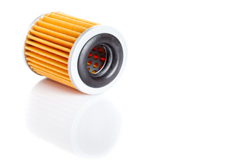 orange paper car filter lies on its side on a white background with reflection and free space for text, isolated spare part on a white background with copy space.