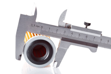 Calibration with a caliper of the outer size of a round paper car filter orange color, the process of measuring the details isolated on a white background with reflection.