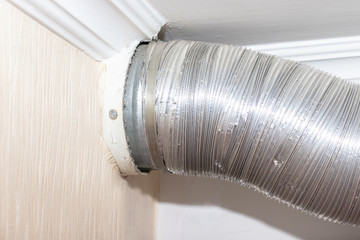 Expandable metallic aluminium corrugated air-conditioning ventilation pipe in kitchen connecting a cooker hood and a ventilation air shaft