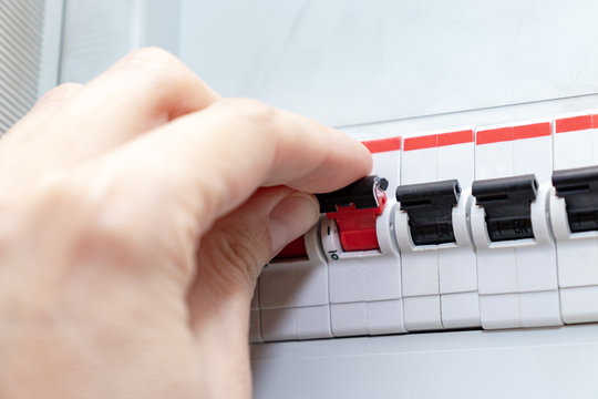 Hand switching the automatic switches of electricity in the house electrical shield - electricity control panel with circuit breakers
