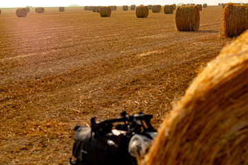 Touring bike hidden by a hay ball in a big orangee-colored field