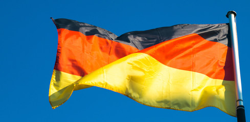 flags of germany waving on background of blue sky