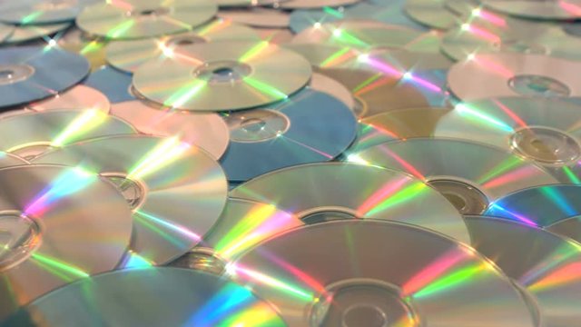 Sliding dolly along endless CD DVD data discs and stopping on a gold oneSliding along a sea of DVD or CD optical discs of gold green and silver, stopping on a gold one.