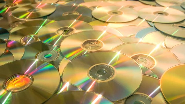 Sliding forward over CD DVD data discs until you drown. Sliding along a sea of DVD or CD optical discs in a forward dolly shot.