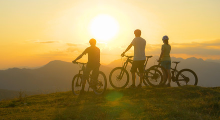 SILHOUETTE: Mountain bikers rest at the grassy mountaintop and observe sunrise.