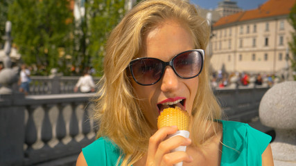CLOSE UP: Tourist girl eating an ice cream cone while exploring Ljubljana.