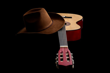 American culture, folk song and country muisc concept theme with a cowboy hat and an acoustic guitar isolated on black background with dramatic lighting