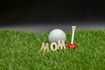 Happy mother's day to golfer with golf ball and flowers are on green grass