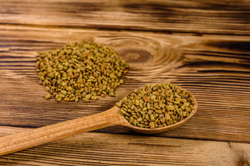 Spoon with fenugreek seeds on wooden table