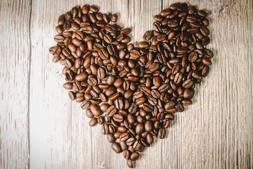 a handful of coffee beans in the shape of a heart, after roasting on the table, close-up. roasted heart-shaped coffee beans on the table, selective focus. Romantic theme.