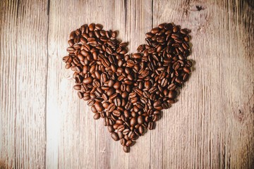 a handful of coffee beans in the shape of a heart, after roasting on the table, close-up. roasted heart-shaped coffee beans on the table, selective focus. Romantic theme.