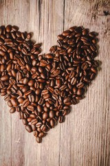 a handful of coffee beans in the shape of a heart, after roasting on the table, close-up. roasted heart-shaped coffee beans on the table, selective focus. Romantic theme.