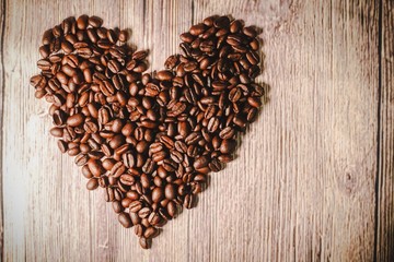 a handful of coffee beans in the shape of a heart, after roasting on the table, close-up. roasted heart-shaped coffee beans on the table, selective focus. Romantic theme.