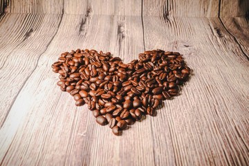 a handful of coffee beans in the shape of a heart, after roasting on the table, close-up. roasted heart-shaped coffee beans on the table, selective focus. Romantic theme.