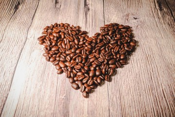 a handful of coffee beans in the shape of a heart, after roasting on the table, close-up. roasted heart-shaped coffee beans on the table, selective focus. Romantic theme.