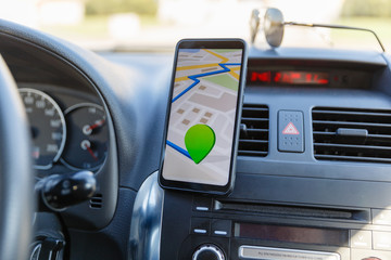 The map on the phone in the background of the dashboard. Black mobile phone with map gps navigation...
