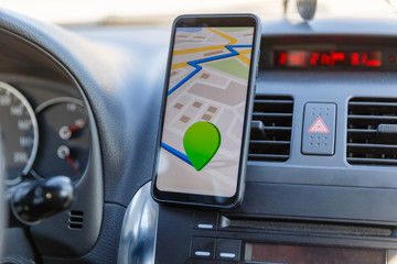 Arrival or destination point on the map in the phone on the dashboard background. Black mobile...