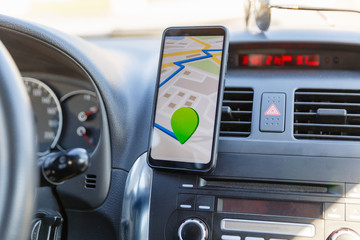 Arrival or destination point on the map in the phone on the dashboard background. Black mobile phone with GPS map navigation is fixed in the installation. App map for traveling with route