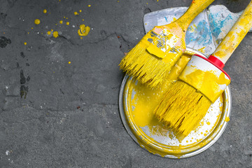 Brushes with yellow paint lies on ground