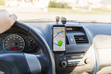 Arrival or destination point on the map in the phone on the dashboard background. Black mobile phone with GPS map navigation is fixed in the installation. App map for traveling with route