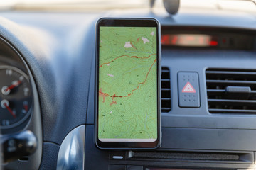 The map on the phone in the background of the dashboard. Black mobile phone with map gps navigation...