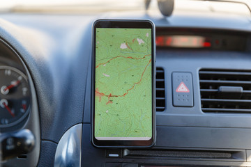 The map on the phone in the background of the dashboard. Black mobile phone with map gps navigation...