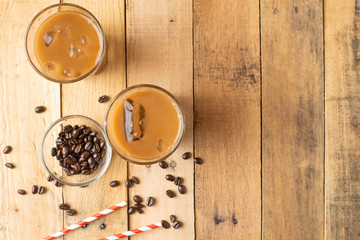 Flat lay. Cold coffee in transparent glasses with ice and straws, on a wooden background, cooling drink, refreshing, summer mood, with copy space