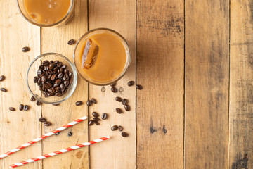 Flat lay. Cold coffee in transparent glasses with ice and straws, on a wooden background, cooling drink, refreshing, summer mood, with copy space
