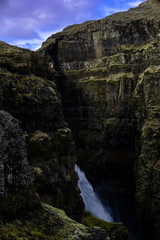 A small part of the Icelandic waterfall Glymur visible behind a rocky cliff