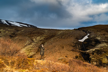 Photographer standing in the afternoon light trying to capture some pictures during the golden hour in the mountains