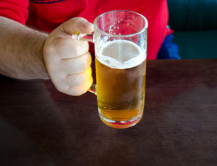 men's rough hands holding a glass of beer