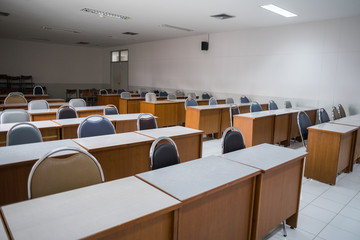 Education concept: Empty college or university classroom with wooden tables and chairs in row without student or teacher in the room. School classroom with window opened, clean and tidy ready for new 