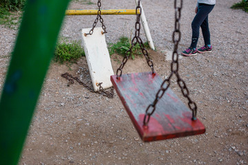 Empty swing in the park and a broken swing in the park.