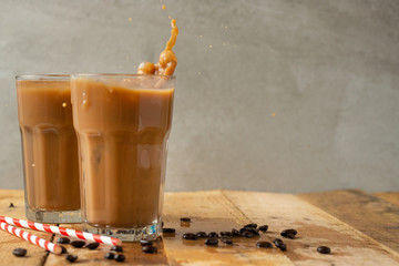 Iced iced coffee in large transparent glasses, poured over milk, with coffee beans on a wooden...