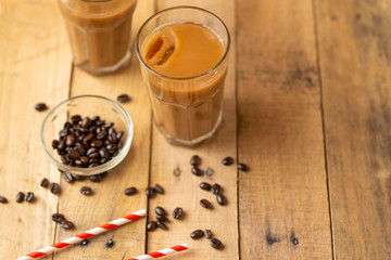Flat lay. Cold coffee in transparent glasses with ice and straws, on a wooden background, cooling drink, refreshing, summer mood, with copy space