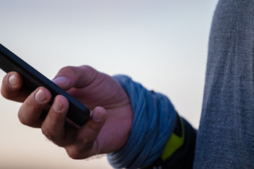 Man holding smart phone in hand with blue wristband on white background.