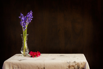 Simple bouquet of purple flowers in a vase with sprig of red flowers on table; table with elegant flowers in vase - Powered by Adobe