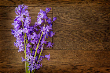 Simple bouquet of small purple flowers in a lay flat format; close up of the blossoms against wood surface