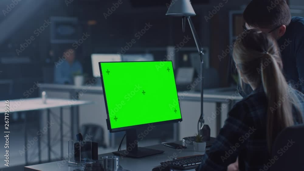 Poster Engineer Working on Desktop Computer, Screen Showing Green Mock-up Screen, Her Male Project Manager Explains Project Specifics. Industrial Design Engineering Facility Office
