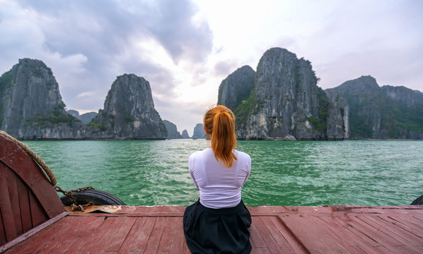 Back view woman traveler sitting on boat looking relaxed among the islands at Halong Bay, Vietnam.