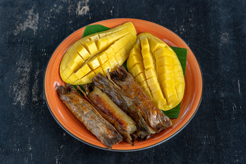 Thai style dessert, yellow mango with banana sticky rice in palm leaves. Yellow mango and sticky rice is popular traditional food of Thailand. Closeup