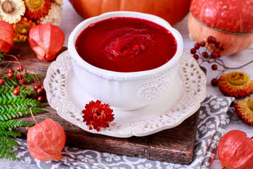 Creamy autumn soup in white plate. Seasonal pumpkin decorations